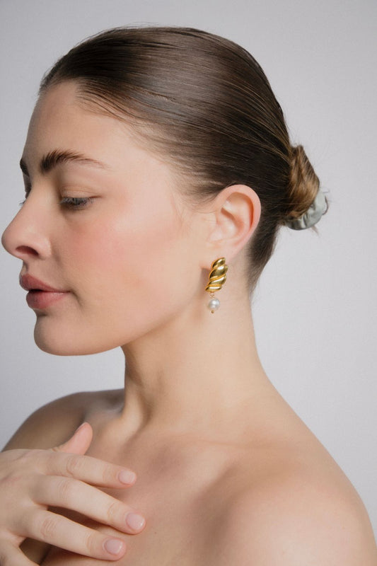 Woman wearing wing shaped earrings with a neutral background