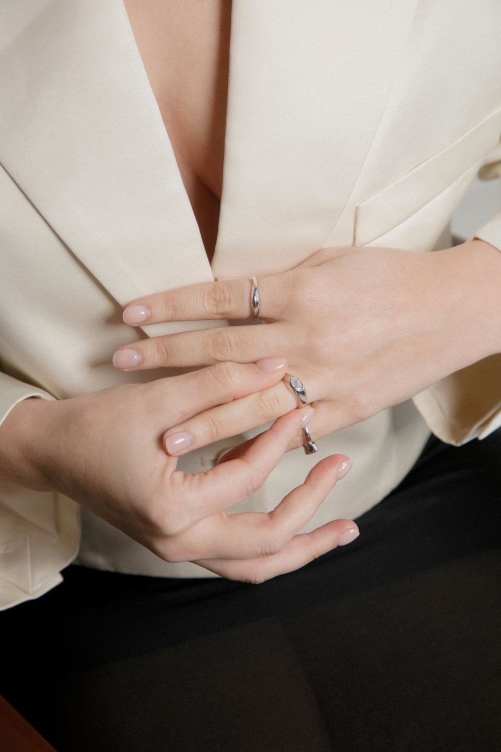 Close-up of two hands with rings on a neutral background