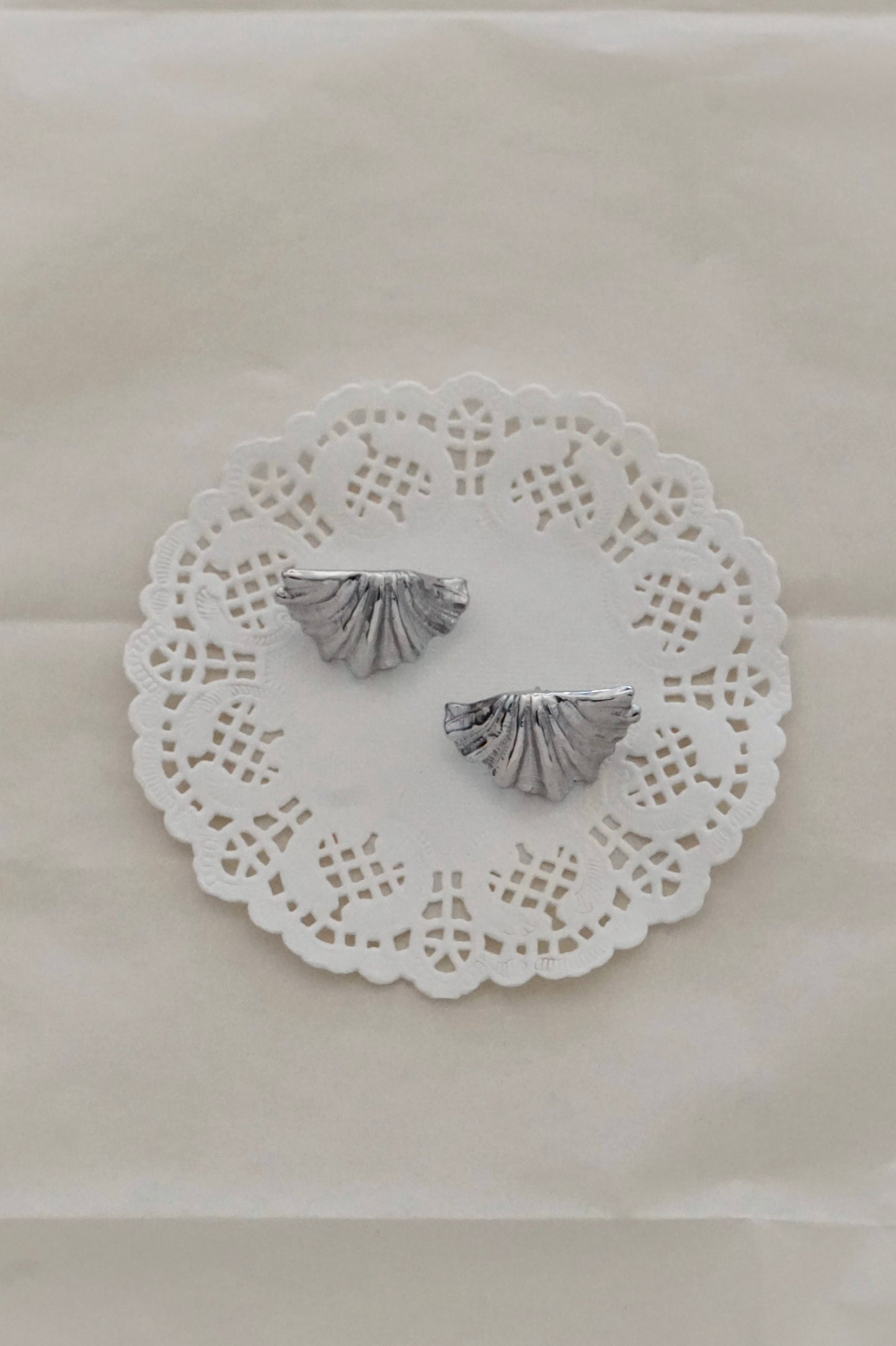 Silver shell earrings on a lace doily