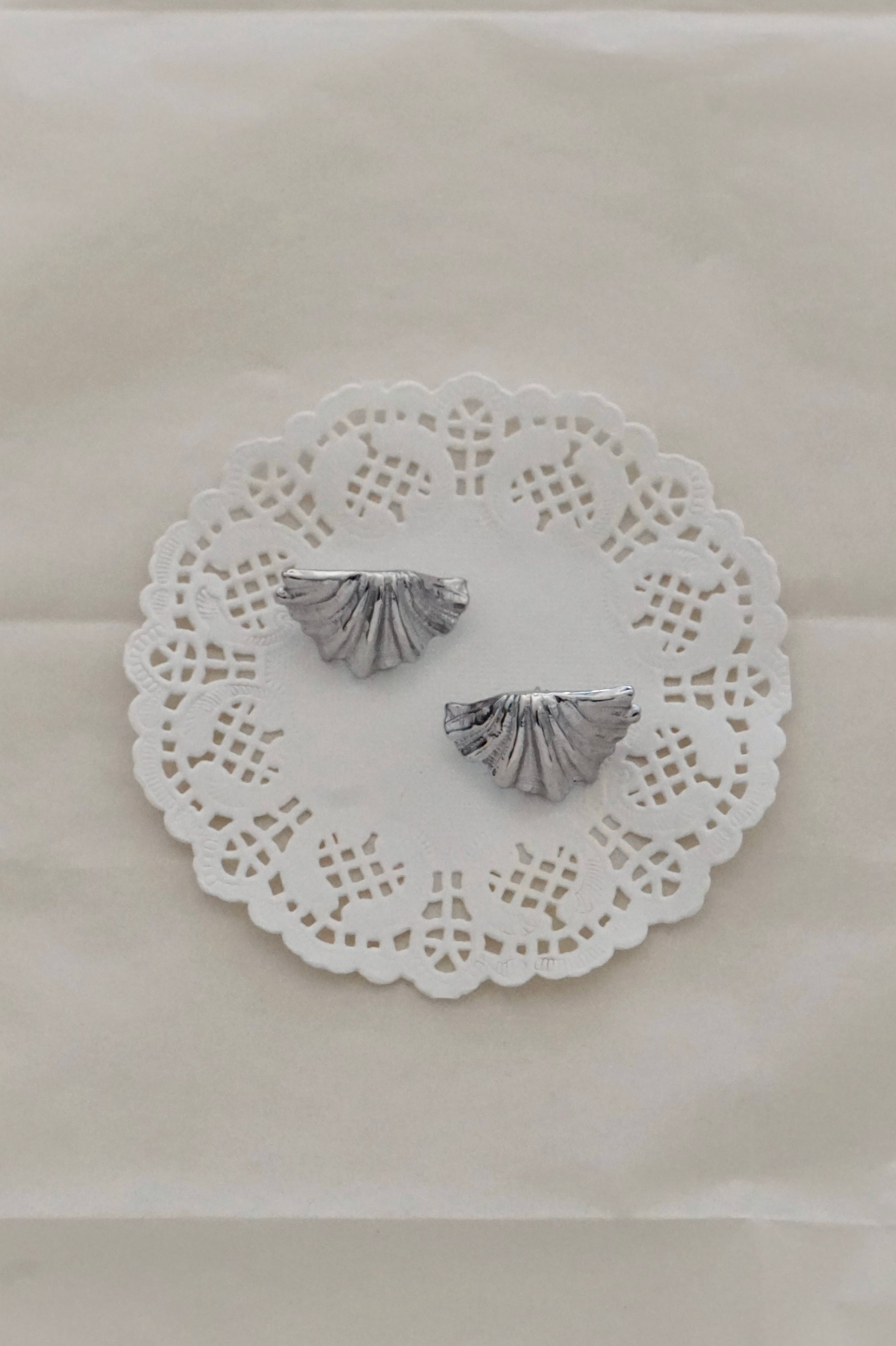 Silver shell earrings on a lace doily